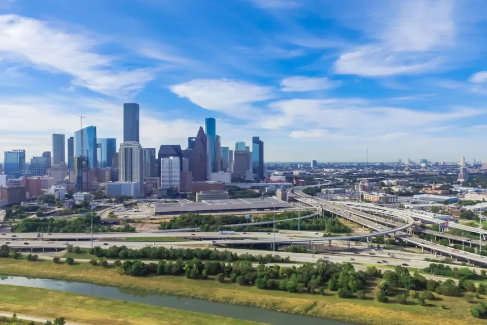 View of Houston freeways and downtown skyline in the background against blue sky with white clouds